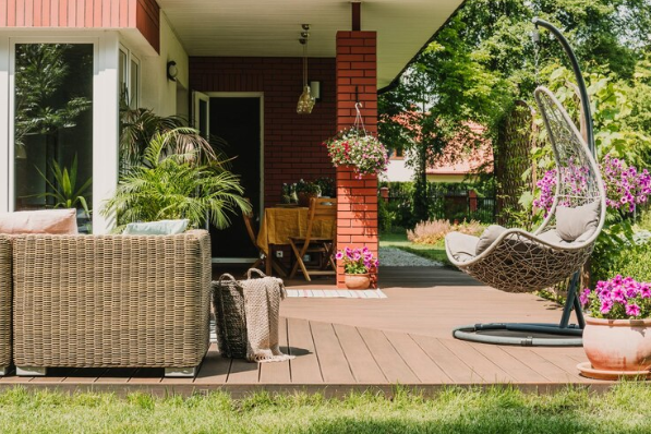 An outdoor space with various flooring types adorned with garden furniture and lots of plants.