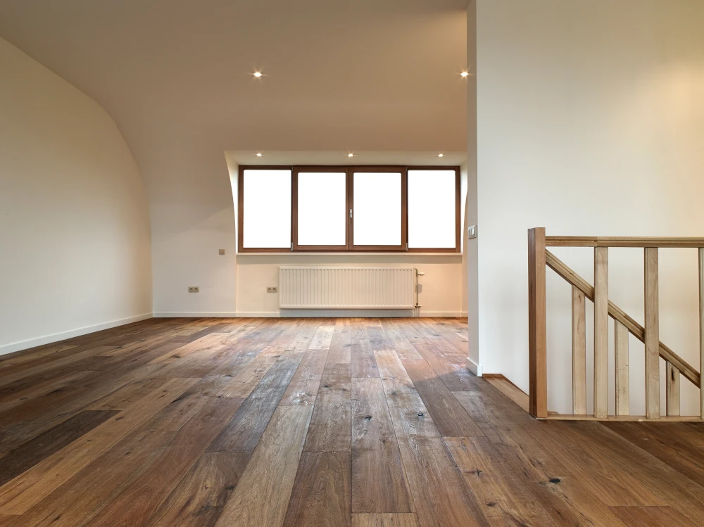 Hardwood flooring installed in a room with white walls and a big window