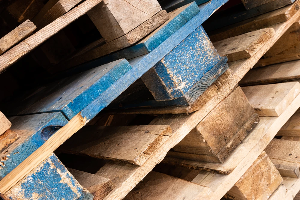 Stacked reclaimed wood pallets representing the importance of using recycled materials for a sustainable home expansion.
