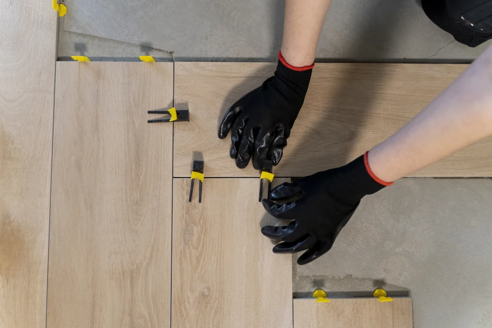 Worker installing a basement’s flooring, representing the importance of insulation for a sustainable home expansion
