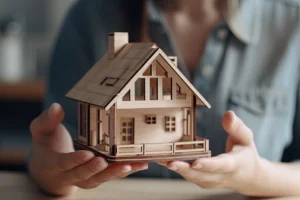 A woman holds a wooden house in her hands, representing the importance of hiring a serious company for home expansion services