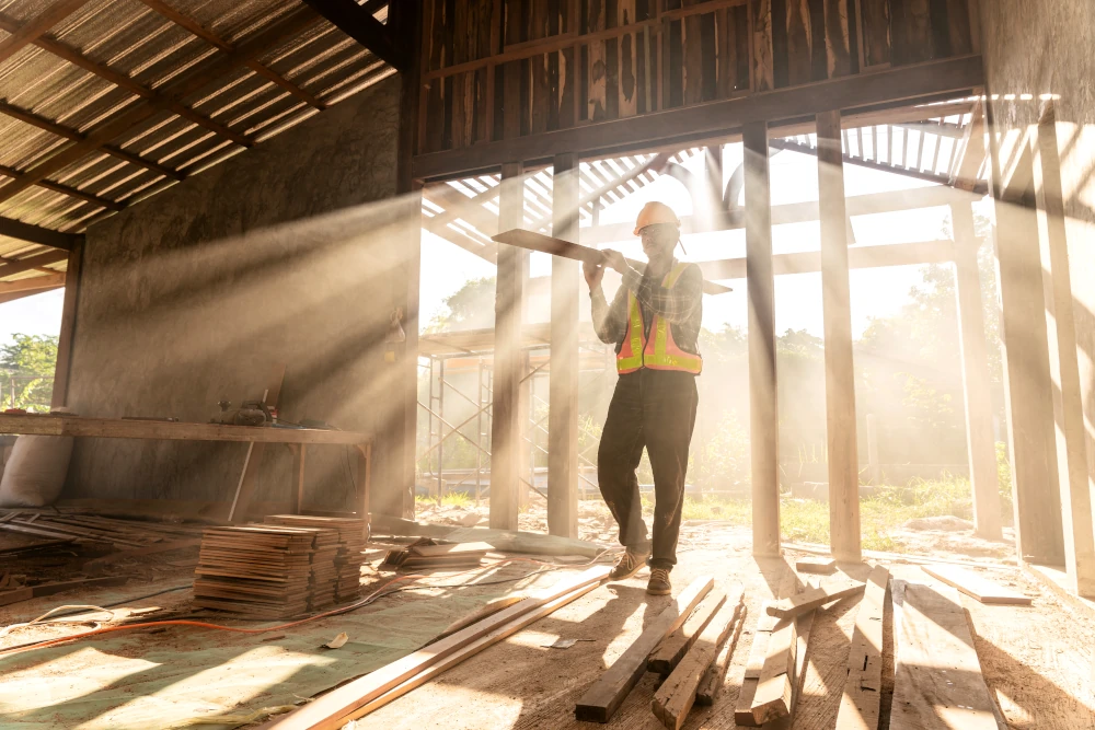 A carpenter holding wooden planks on a construction site, representing Goveias' ability to take care of an entire home expansion with mastery.
