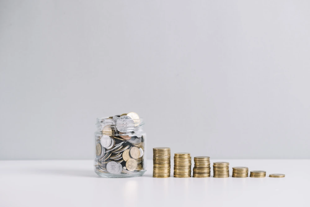 Glass jar full of money and decreasing stacked coins against a white background, representing the importance of having a well-defined budget to avoid any unpleasant surprises in your home expansion project.
