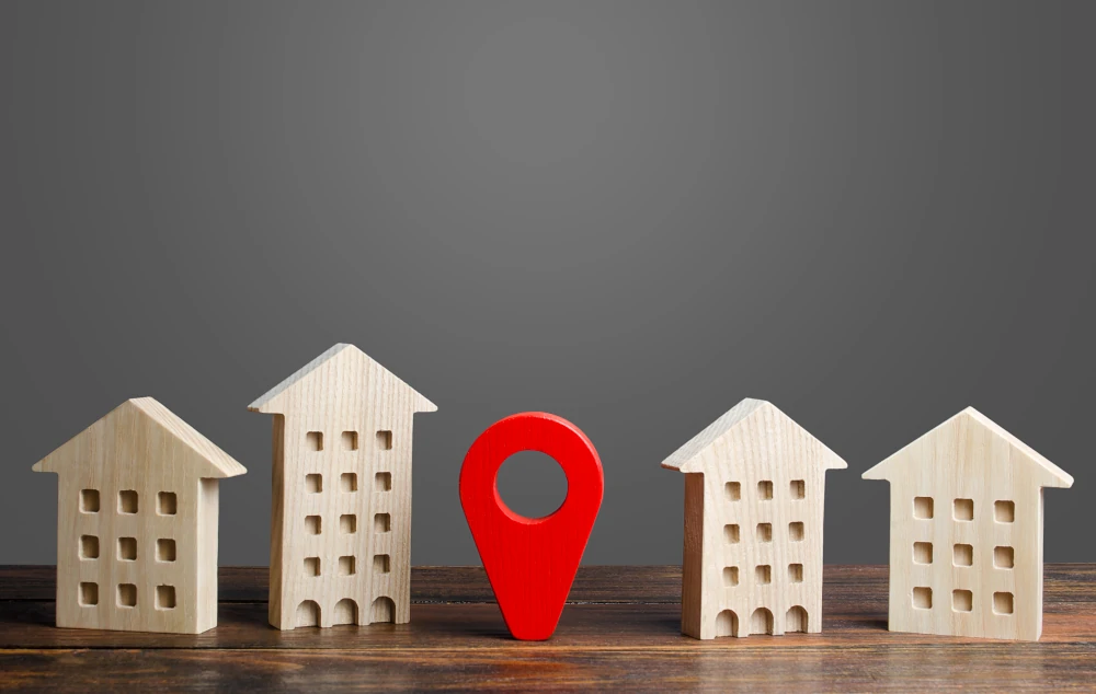 A red location indicator stands between residential buildings, representing the importance of choosing a good location for your property investments.