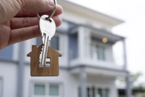 A man holds a house key for his new home, a property investment.