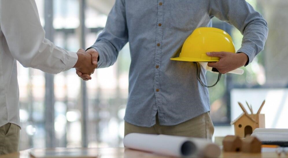 Two men shaking hands, closing a construction contract, representing the importance of choosing top construction companies' services.