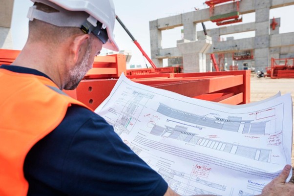 Commercial general contractor on a building site holding a construction plan for the project.