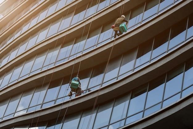 Workers cleaning the facade of a retail building after a commercial building restoration.