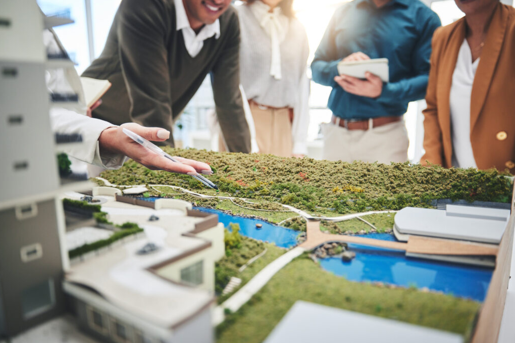 People analyzing a mock-up model of a sustainable commercial construction.